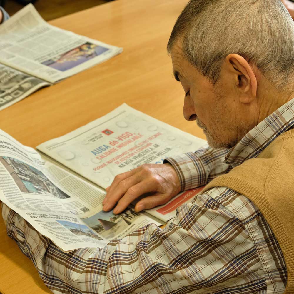 Usuario del centro de día Atlántida leyendo el periódico